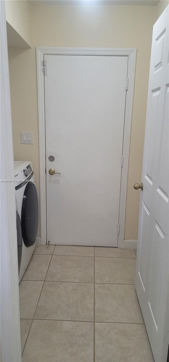 washroom with light tile patterned flooring, laundry area, and washer / clothes dryer