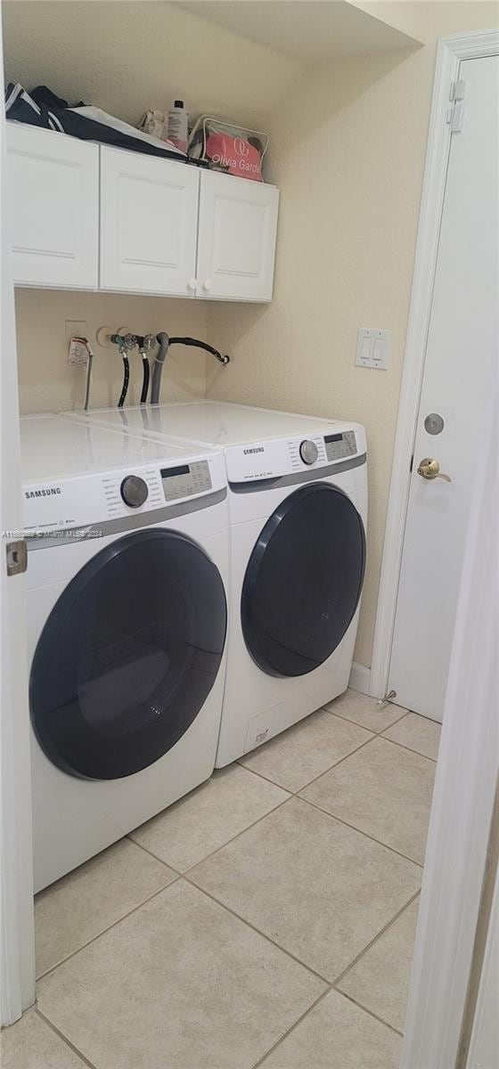 laundry room with cabinets, light tile patterned flooring, and washer and clothes dryer