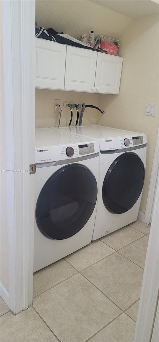 laundry area featuring washer and dryer, cabinet space, and light tile patterned flooring