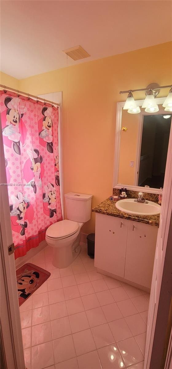 bathroom with a shower with shower curtain, tile patterned floors, vanity, and toilet