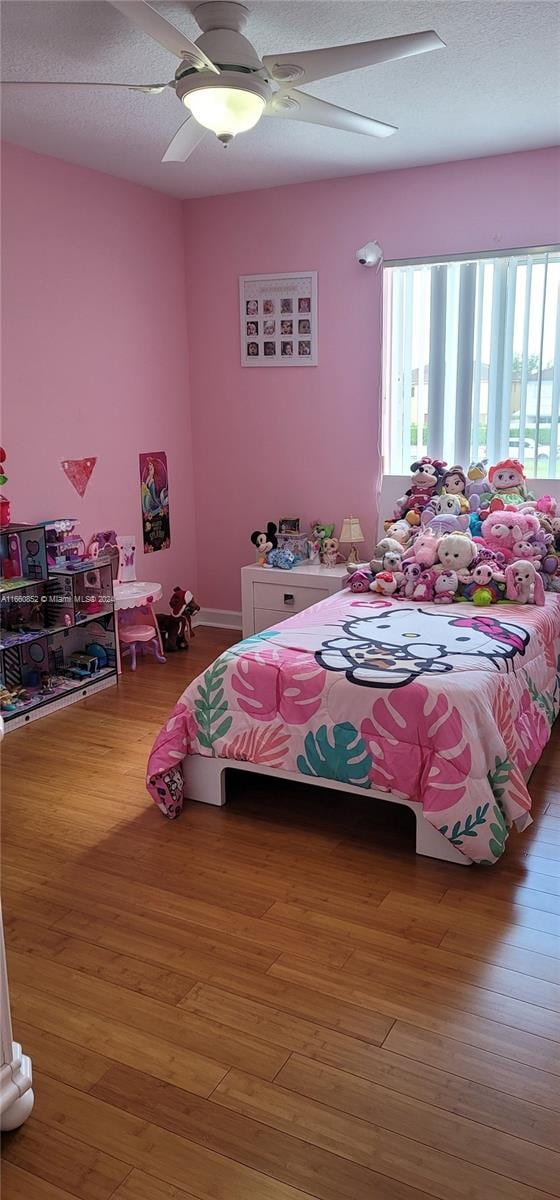 bedroom with ceiling fan, hardwood / wood-style flooring, and a textured ceiling