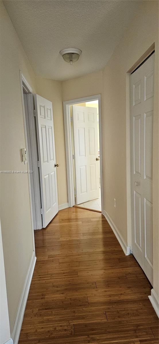 hall featuring a textured ceiling and dark wood-type flooring