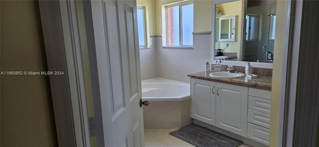 bathroom featuring a relaxing tiled tub, tile patterned floors, and vanity