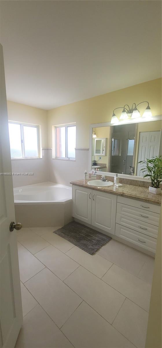 full bath with vanity, a bath, and tile patterned flooring