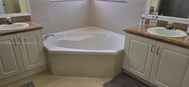 bathroom with tile walls, tile patterned floors, tiled tub, and vanity