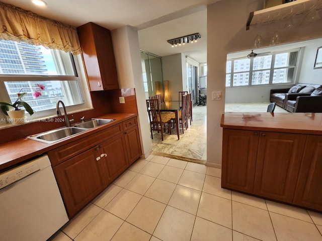 kitchen featuring ceiling fan, light tile patterned floors, dishwasher, and sink