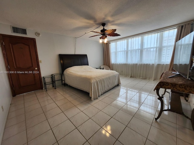 bedroom featuring a textured ceiling, light tile patterned floors, and ceiling fan