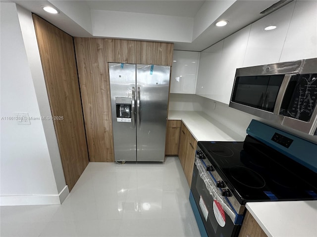 kitchen featuring light tile patterned floors, appliances with stainless steel finishes, and white cabinets