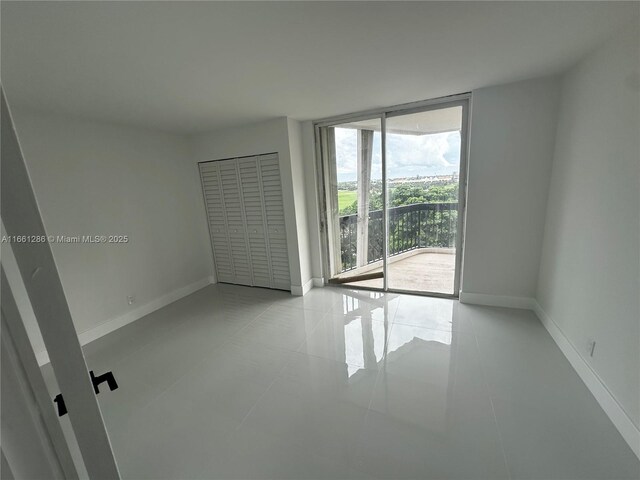 spare room with light tile patterned floors and a wall of windows