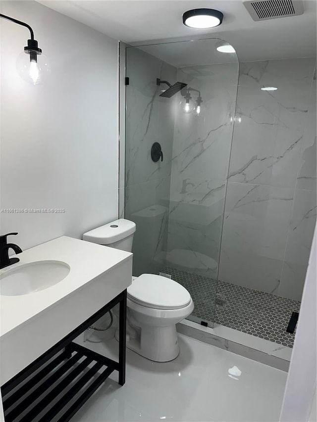 bathroom featuring tiled shower, vanity, and toilet