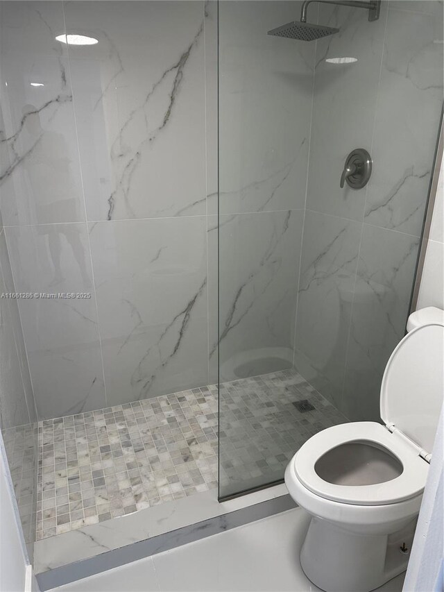 bathroom featuring toilet and a tile shower