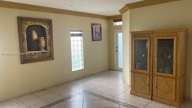 spare room featuring crown molding and light tile patterned floors