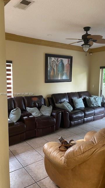 tiled living room with ornamental molding and ceiling fan