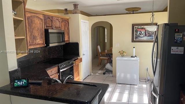 kitchen with kitchen peninsula, hanging light fixtures, decorative backsplash, stainless steel appliances, and light tile patterned floors