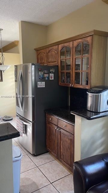 kitchen with pendant lighting, a textured ceiling, light tile patterned floors, and stainless steel fridge