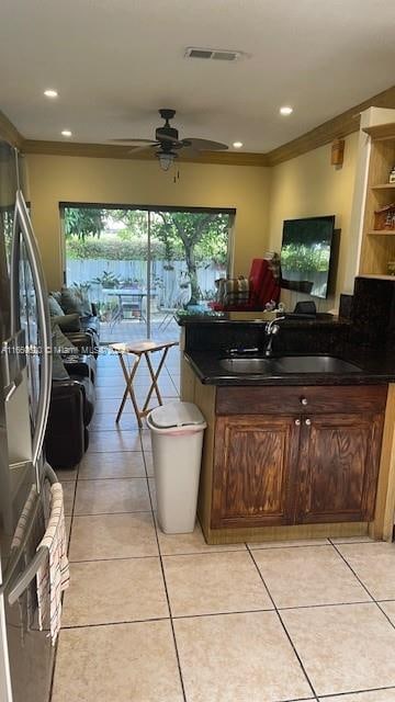 kitchen with light tile patterned floors, crown molding, sink, and ceiling fan