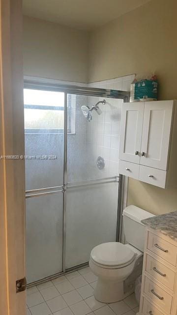 bathroom featuring vanity, toilet, tile patterned floors, and a shower with shower door