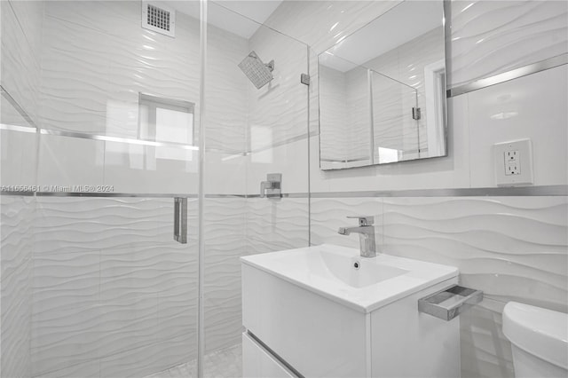 bathroom featuring vanity, tile walls, a shower with shower door, and toilet