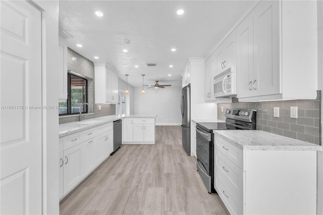 clothes washing area with cabinets, light wood-type flooring, sink, ceiling fan, and washing machine and dryer