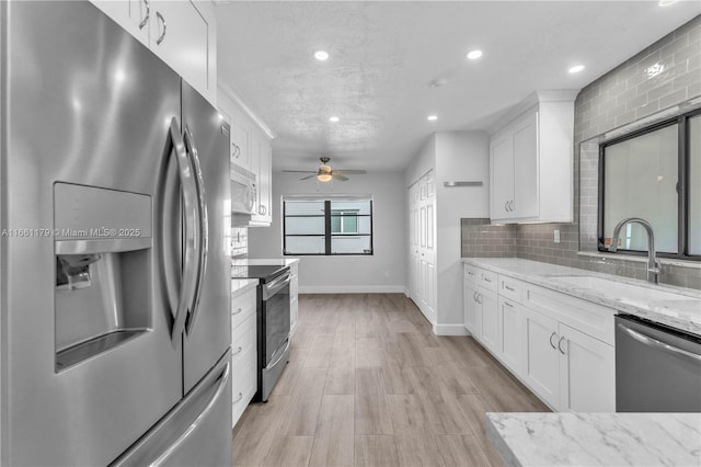 kitchen with appliances with stainless steel finishes, sink, white cabinets, and decorative backsplash