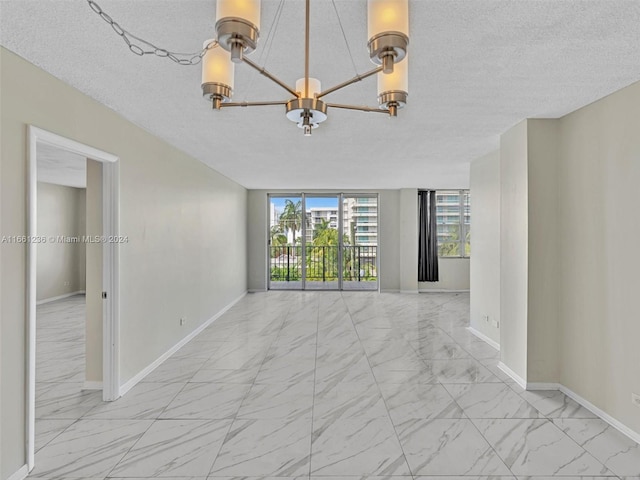 spare room featuring an inviting chandelier and a textured ceiling