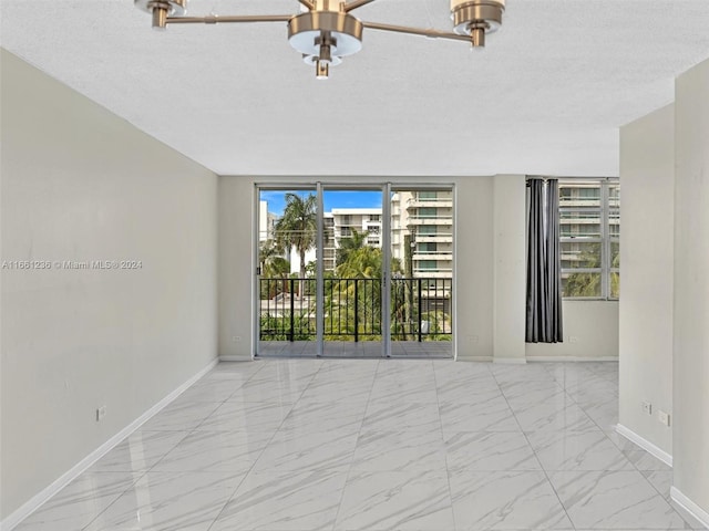 empty room with a textured ceiling, ceiling fan, and a wealth of natural light