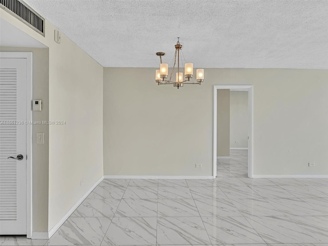 spare room featuring a textured ceiling and a chandelier