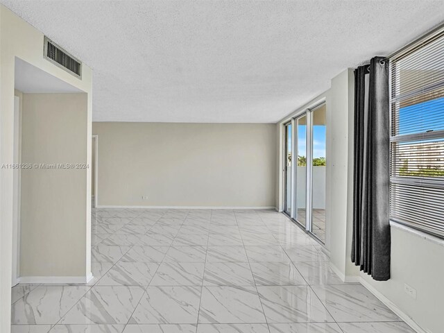 empty room featuring a textured ceiling and plenty of natural light