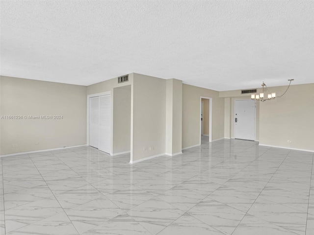 spare room featuring a chandelier and a textured ceiling