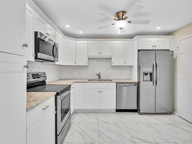 kitchen featuring light stone counters, sink, white cabinets, appliances with stainless steel finishes, and ceiling fan