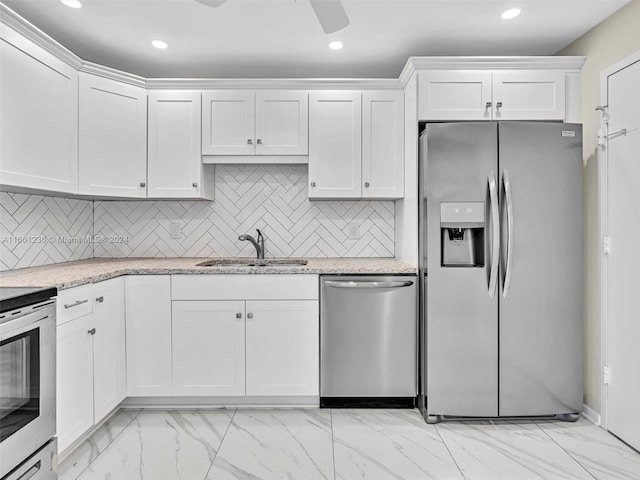 kitchen with ceiling fan, light stone counters, sink, white cabinetry, and appliances with stainless steel finishes