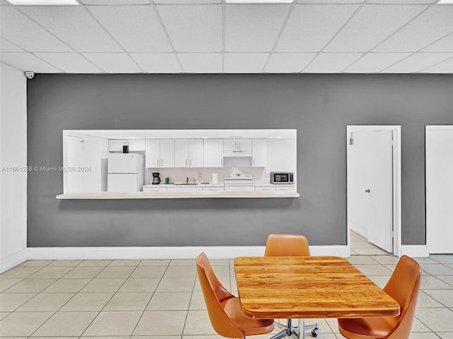 dining room with a drop ceiling, sink, and light tile patterned floors