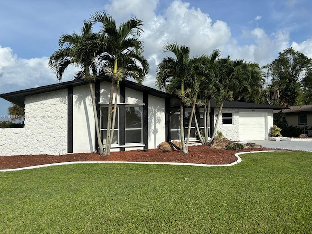 view of front of home with a garage, a sunroom, and a front lawn