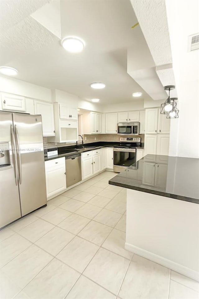 kitchen with kitchen peninsula, white cabinetry, light tile patterned floors, and stainless steel appliances