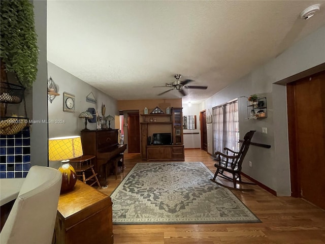 living room featuring ceiling fan, a textured ceiling, and hardwood / wood-style floors