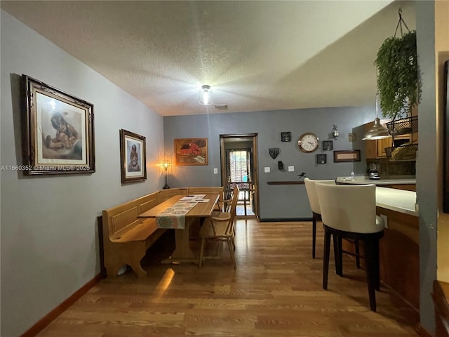 kitchen with light hardwood / wood-style floors, kitchen peninsula, decorative light fixtures, black appliances, and a kitchen bar