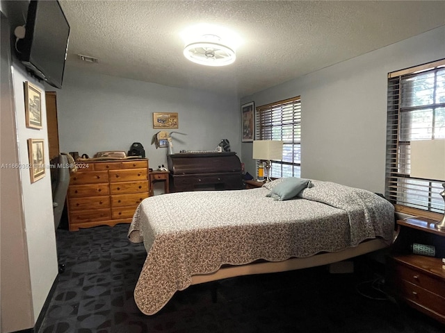 carpeted bedroom with multiple windows and a textured ceiling