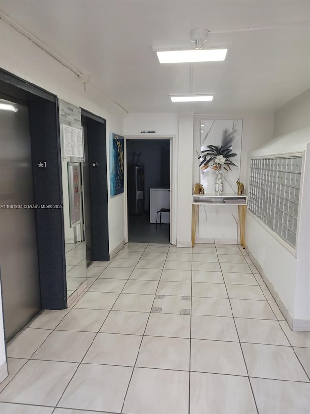 hallway featuring electric water heater, light tile patterned floors, and a mail area