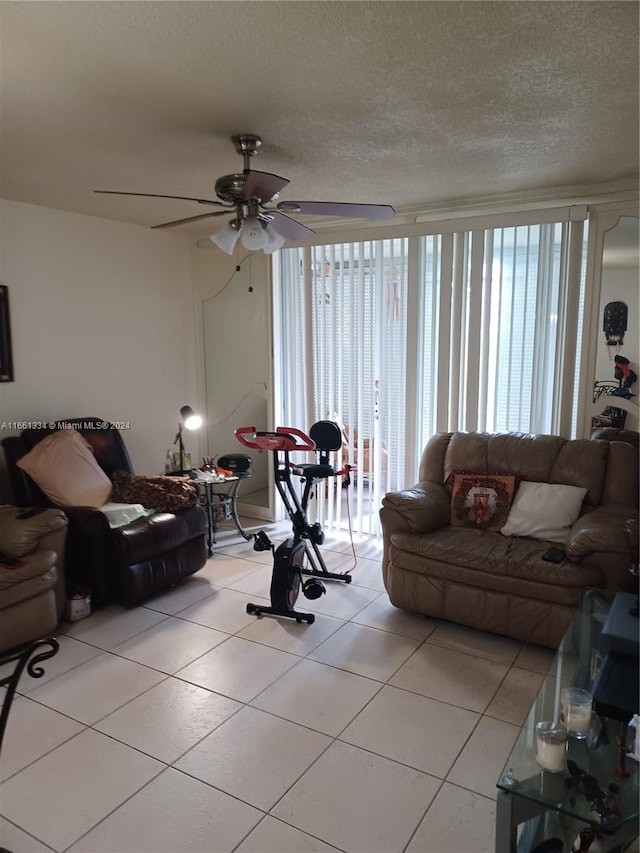 living room featuring a textured ceiling, light tile patterned floors, and ceiling fan