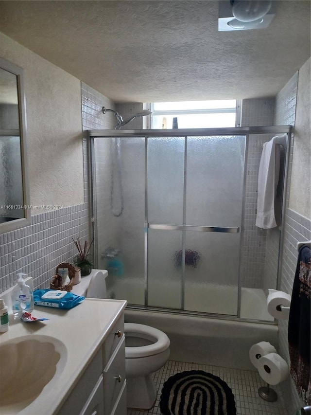 full bathroom with tasteful backsplash, vanity, a textured ceiling, bath / shower combo with glass door, and toilet