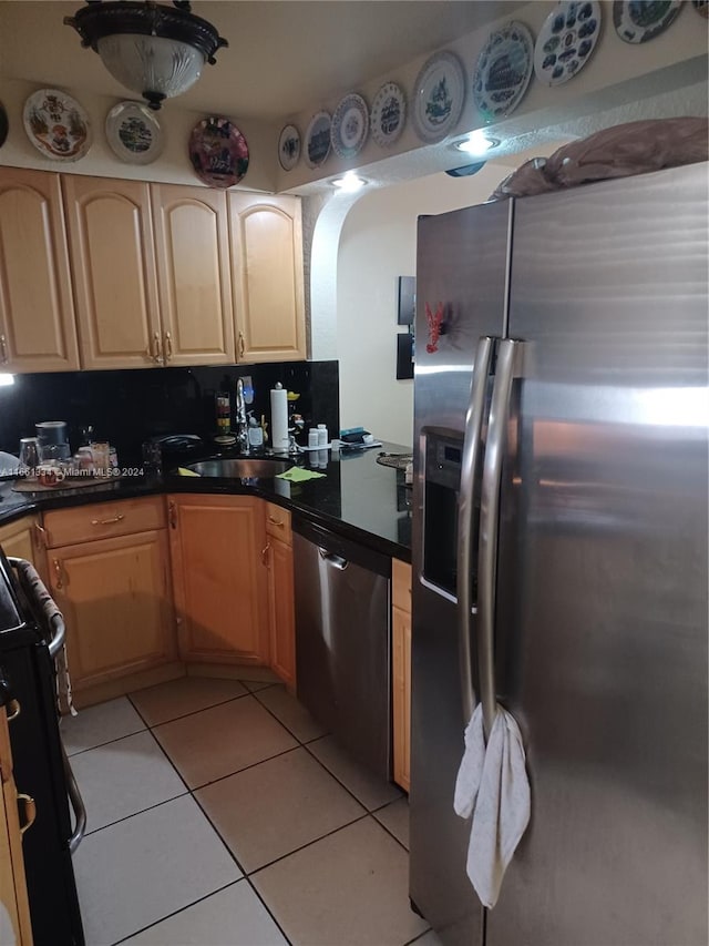 kitchen with appliances with stainless steel finishes, light tile patterned flooring, and light brown cabinets