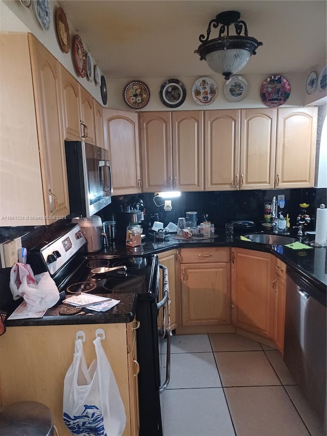 kitchen with light brown cabinetry, light tile patterned flooring, stainless steel appliances, and backsplash