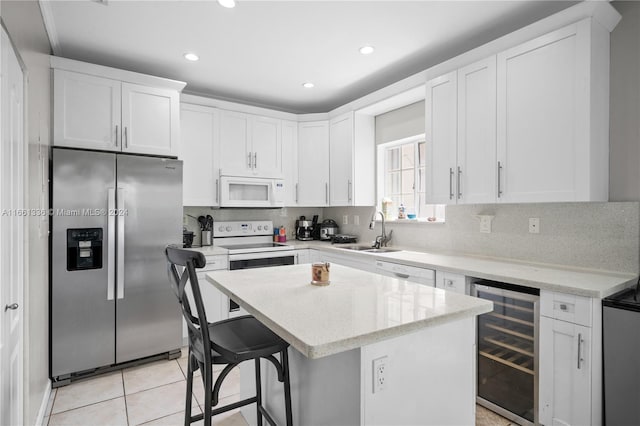 kitchen featuring a kitchen island, white appliances, white cabinetry, and wine cooler