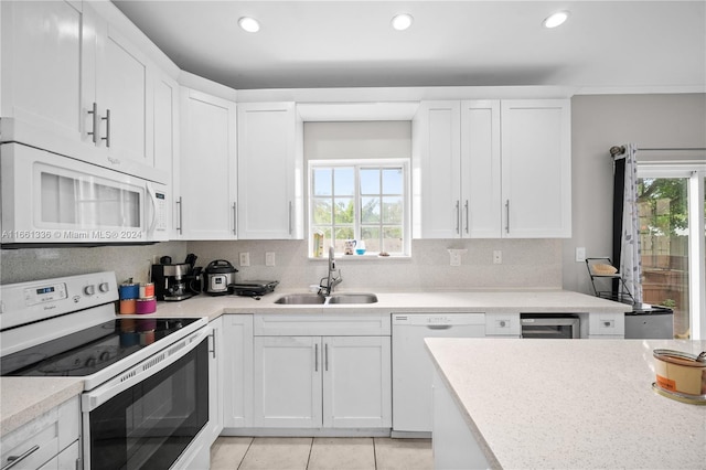 kitchen with a wealth of natural light, sink, white cabinets, and white appliances