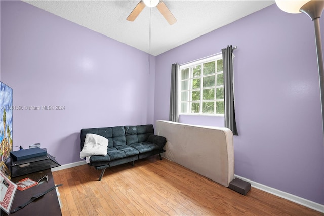 living area with wood-type flooring, a textured ceiling, and ceiling fan