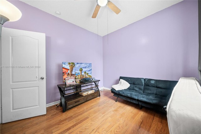 living room with ceiling fan, wood-type flooring, and vaulted ceiling