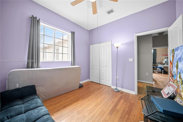 living area featuring a textured ceiling, light hardwood / wood-style floors, and ceiling fan