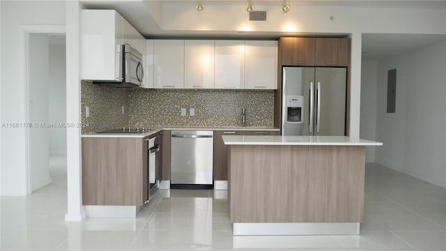 kitchen with white cabinets, appliances with stainless steel finishes, backsplash, and a kitchen island