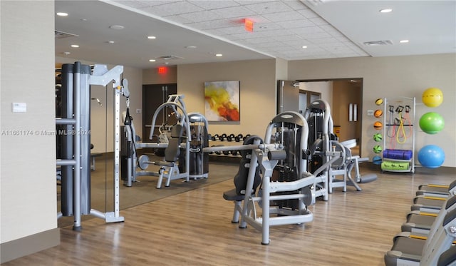 gym with light wood-type flooring and a paneled ceiling