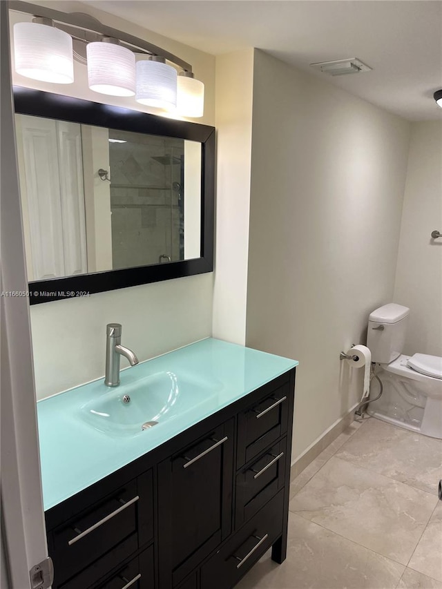 bathroom featuring a shower with shower door, vanity, and toilet